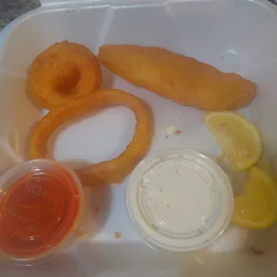 a container of onion rings, onion rings, and ketchup