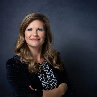 Professional studio headshot, dark blue background
