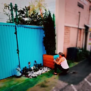 Kelly painting the outside treebox of the Art Shack