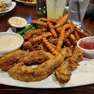 Chicken tenders with sweet potato fries and green beans. Gravy left front. Back left dessert-like concoction for fries.