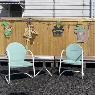 two chairs and a table in front of a fence