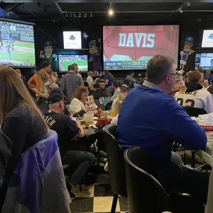 a large group of people sitting at tables watching a baseball game