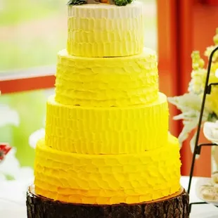 a three tiered cake with yellow frosting