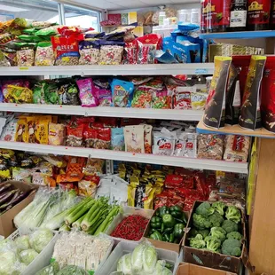 Packaged items on shelves and produce on the ground...