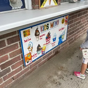 a little girl standing in front of an ice cream shop