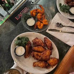 two plates of chicken wings and dipping sauces