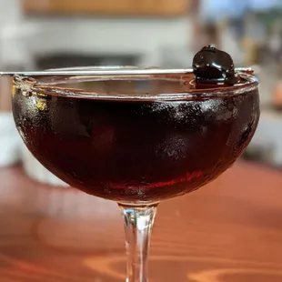 a glass of wine with a black olive garnish