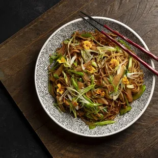 a plate of noodles with chopsticks