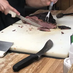 shows a man cutting meat on a cutting board