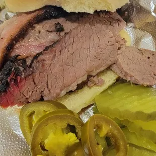 Small Brisket sandwich with pickles and jalapenos.