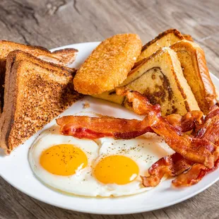 a plate of bacon, toast, and eggs