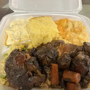 Caribbean oxtails with Mac and cheese, potato salad, and corn bread