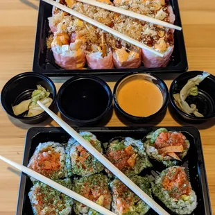 two trays of sushi with chopsticks
