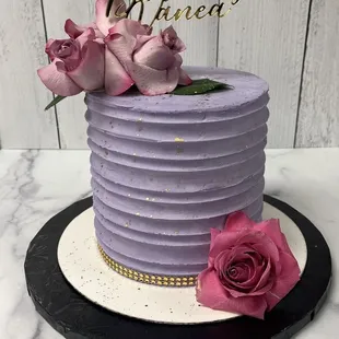 a purple birthday cake with pink roses