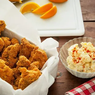 a tray of chicken nuggies and a bowl of mashed potato salad