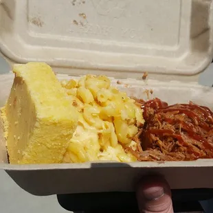 a hand holding a take out container of food