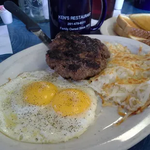 Two eggs sunny side up with chopped steak and hash browns.
