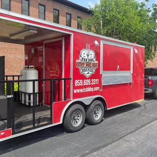 a red food truck parked in front of a brick building