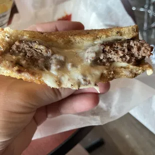 a hand holding a half eaten sandwich