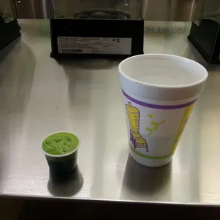 a green smoothie and a plastic cup