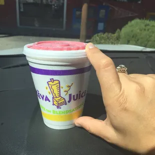 a hand holding a cup of keva juice
