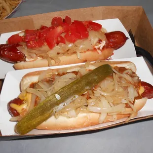 wo hotdogs with onions and a pickle