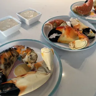 two plates of crab legs and two bowls of dipping sauce