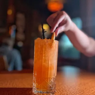 a hand reaching for a cocktail
