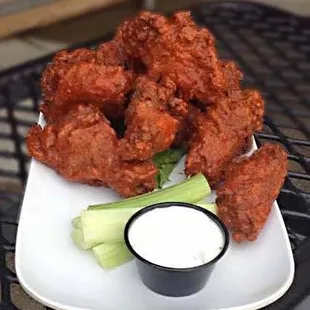 a plate of buffalo wings with celery and ranch dressing