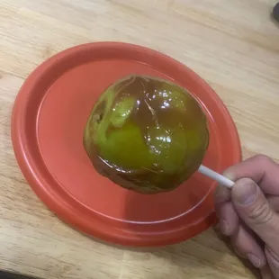 a person dipping a chocolate covered apple on a red plate