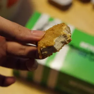 a hand holding a half eaten sandwich