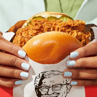 a woman holding a chicken sandwich