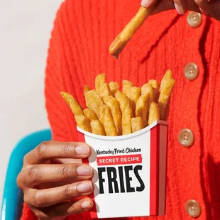 a woman holding a box of fries