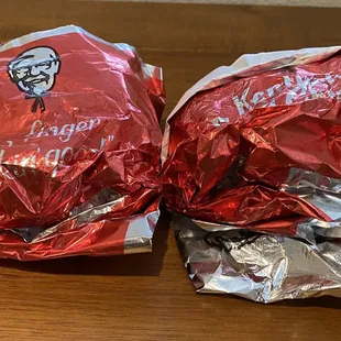 two wrapped sandwiches on a wooden table