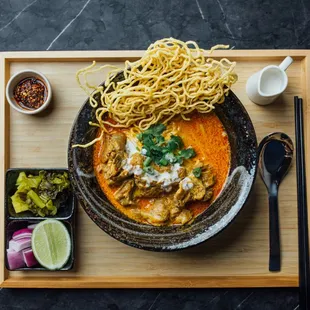 Egg noodles, stewed beef simmered in Khao Soi curry. Topped with crispy egg noodles, then served with pickled mustard, red onions, lime, and