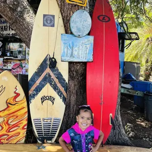 a little girl standing in front of surfboards