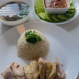 Chicken with rice cooked in chicken rice steamed with chicken on top fresh cilantro served with spicy sauce.