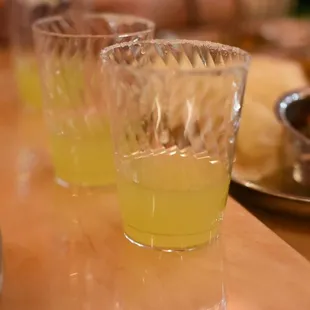 three glasses of yellow liquid on a table