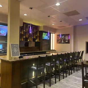 a bar with chairs and televisions