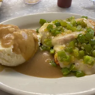 Smothered chicken with onions, peppers and cheese with mashed potatoes and gravy.