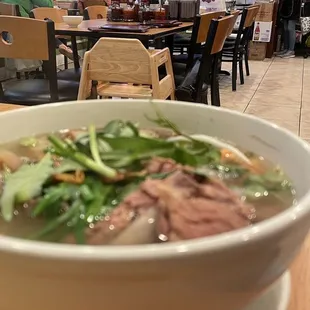 a bowl of soup with meat and greens