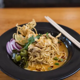 a plate of noodles with chicken and vegetables