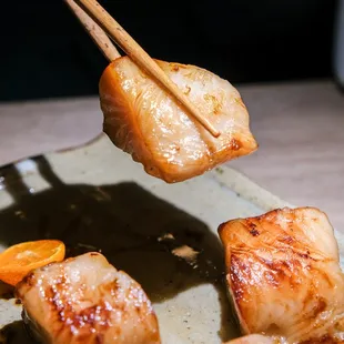 a person holding chopsticks over a plate of food