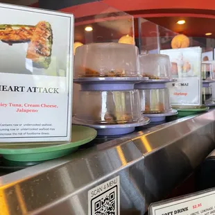 Conveyor belt sushi with signs of what the different rolls are