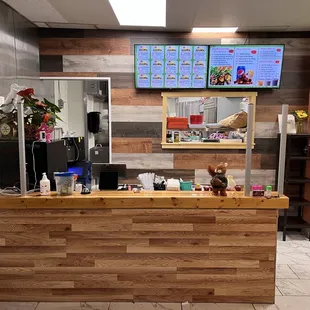 a restaurant counter with a menu on the wall