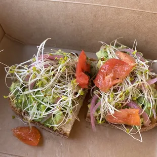 a sandwich with sprouts and tomatoes