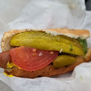 a hot dog with pickles and tomatoes