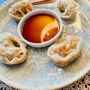a plate of dumplings and dipping sauce