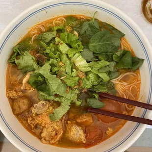 a bowl of soup with chopsticks