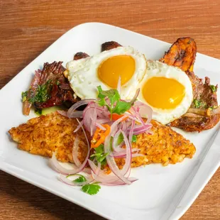Vaca Frita con Tacu Tacu- Grilled flat steak topped with caramelized onion, fried plantain, two eggs and Tacu Tacu (Peruvian rice and beans)